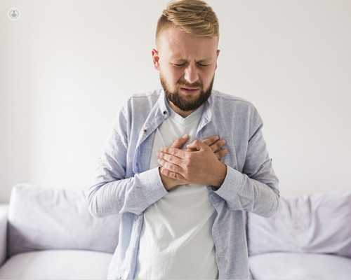 Man with heartburn, holding his hands to his chest with a pained expression