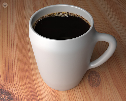 A white mug filled with coffee on a wooden table