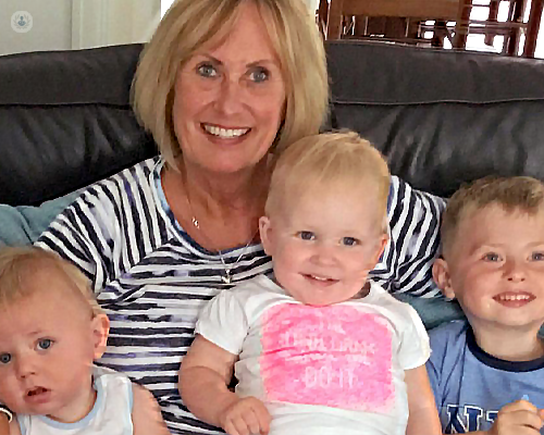 Ms Louise Kean and her grandchildren, smiling, sat on a sofa