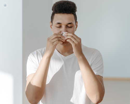 Young man blowing his nose carefully after having a perforated eardrum