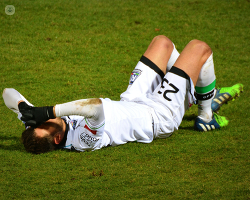 Professional footballer with an injury, lying on the ground