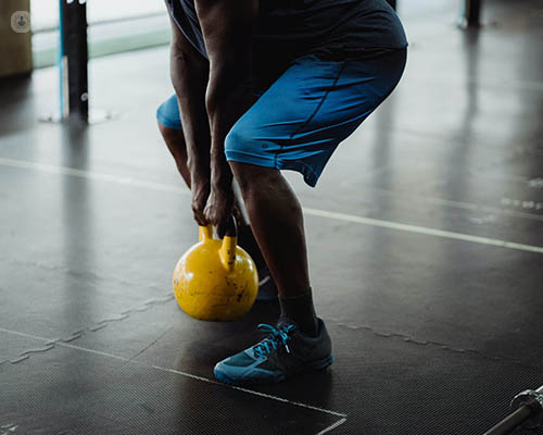 A man uses a dumbell to exercise, putting pressure on his knees.