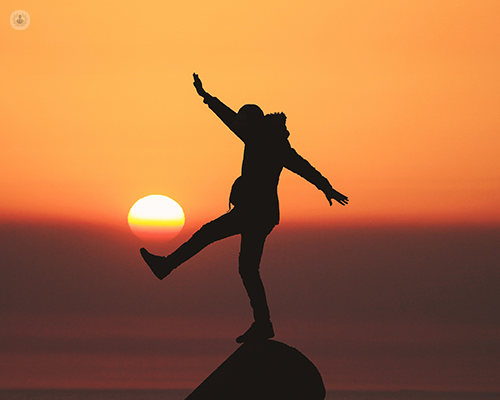 Man balancing on a rock set against a golden sunset