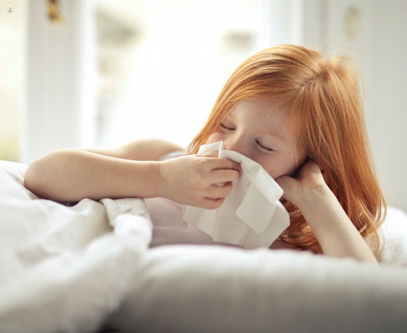 Young girl holding a tissue to her nose