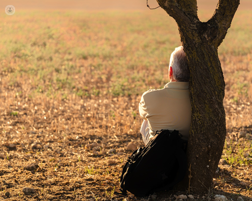 Man, who has recovered from a herniated disc, sitting and relaxing against a tree