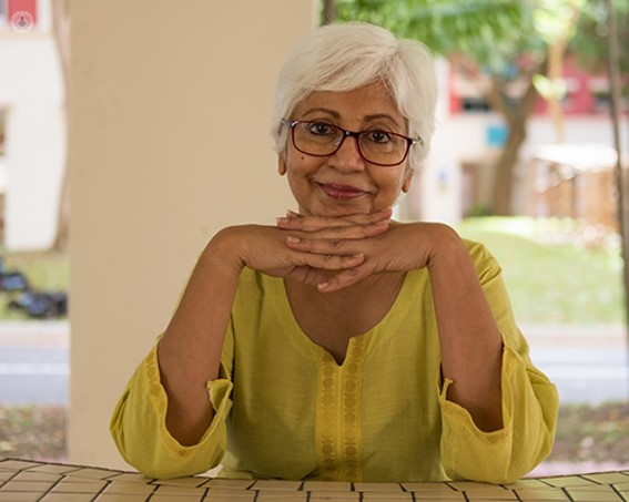 Older lady sat smiling, wearing glasses
