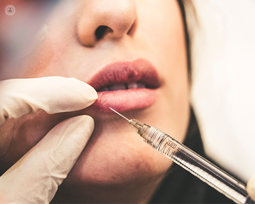A close up of a woman's face in which she is having an injection in her lip