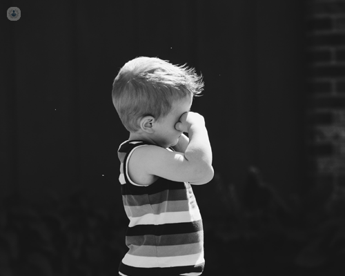 Black and white photo of little boy rubbing his eyes
