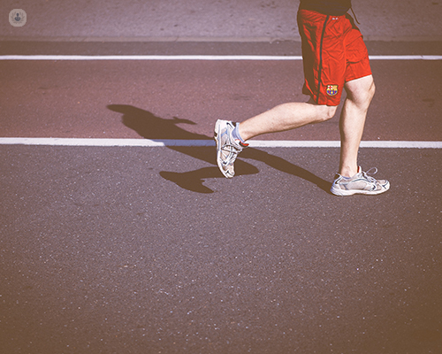 Man running on track. Knees are bent.