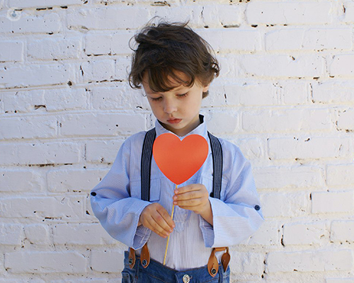 A young child holding a paper cutout of a heart