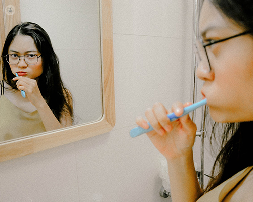Girl brushing her teeth in the mirror