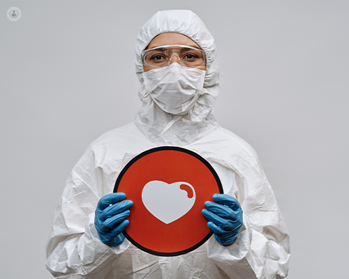 Doctor wearing hazmat suit and mask, holding a heart sign
