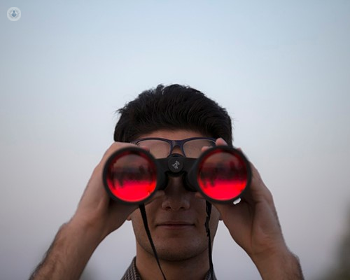 Man holding up and looking through binoculars.