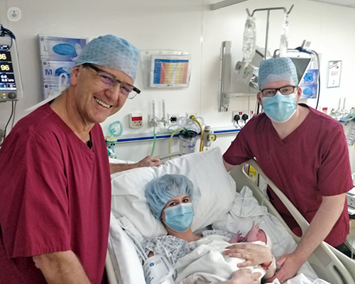 Mr Barnick with a patient, their patient's newborn child and a colleague post-caesarean.