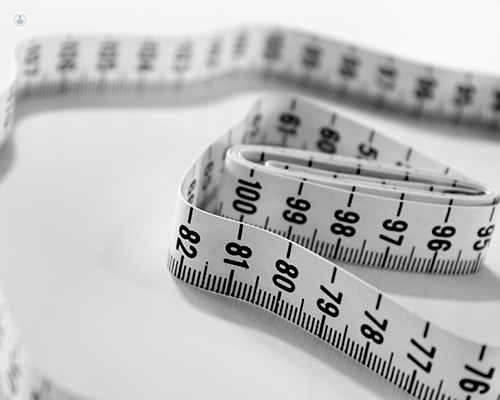 A tape measure laid out on a plain white surface.