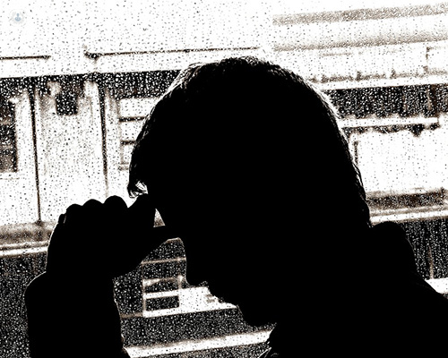 Black and white photo of a depressed man sat by a rainy window