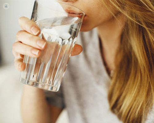 A women is holding a clear glass of water to her lips. In order to begin the capsule endoscopy, she simply needs to consume the capsule with water.