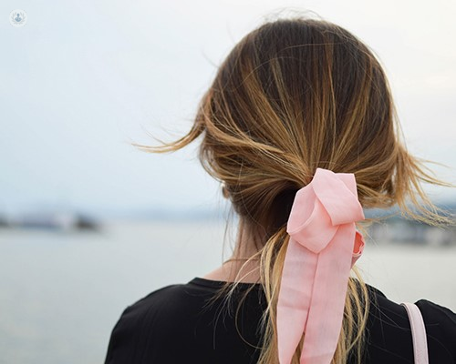 Girl wearing pink bow in her hair looking out to sea