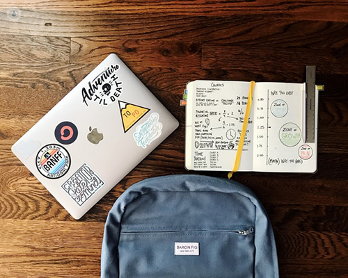 A laptop, notebook and backpack on a desk. 