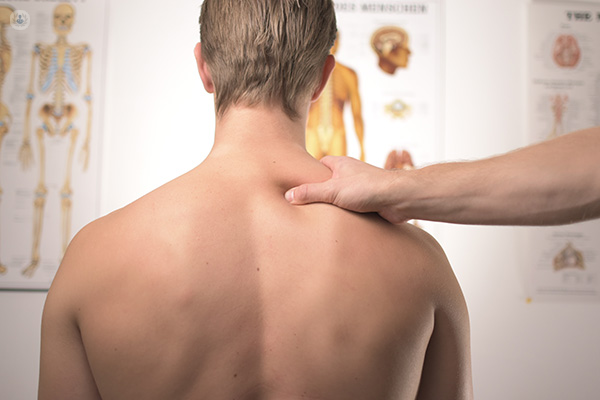 Doctor checks and massages patient with back pain