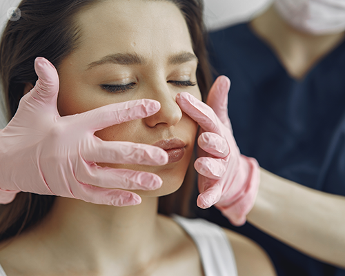 A medical professional's gloved hands lightly pressing on the nose of a patient
