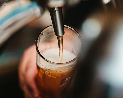 A glass of cold beer being poured from a beer tap. Alcohol can be a cause of liver disease.